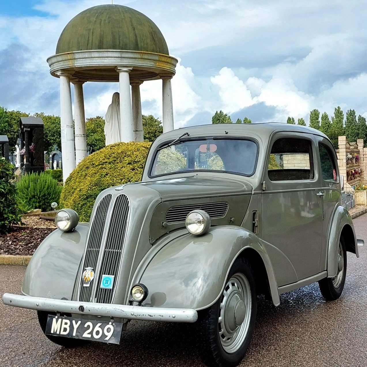 Grey Ford Popular 103E vintage car in front of classical domed pavilion structure