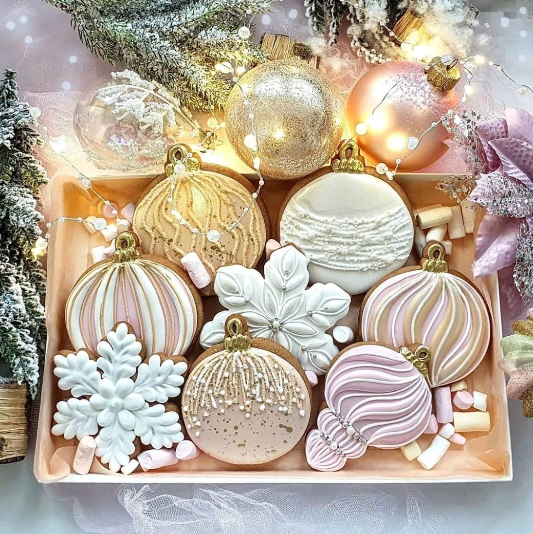 Pastel-colored Christmas cookies shaped as ornaments and snowflakes on a pink tray with holiday decorations