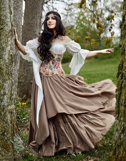 Woman wearing Renaissance-style corset dress with flowing skirt in outdoor park setting