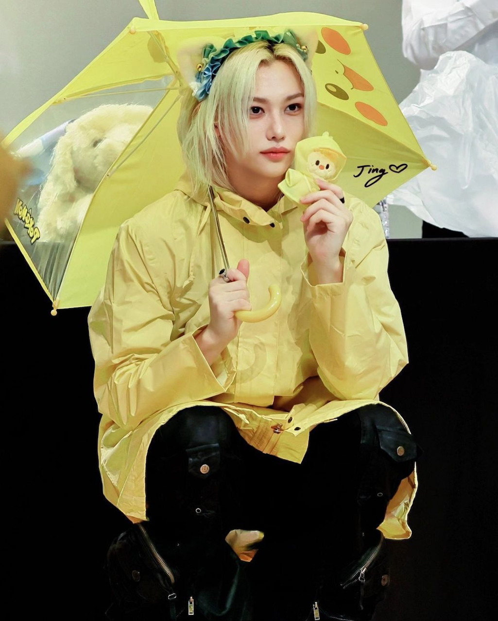 Person with blonde hair in yellow jacket holding yellow umbrella