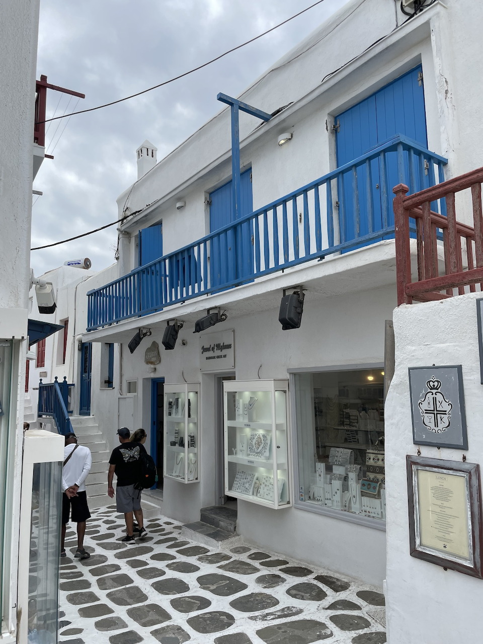 Whitewashed building with blue balcony and shutters on a cobblestone street in Mykonos, Greece