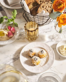 Overhead view of white marble table with desserts, flowers, and golden drink glass
