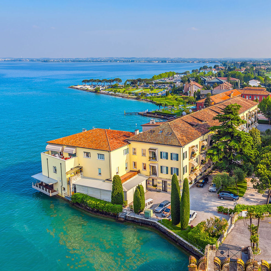 Aerial view of waterfront villas with orange roofs on turquoise Mediterranean coast