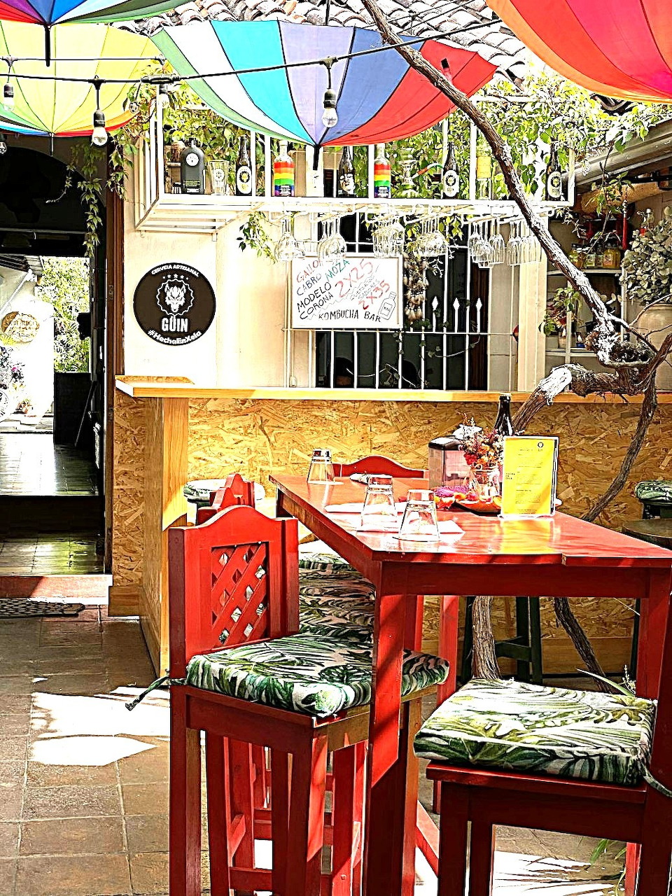 Colorful patio cafe with red furniture under rainbow umbrellas and plants