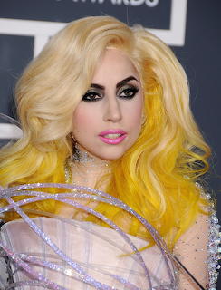 Lady Gaga with blonde and yellow hair, dramatic eye makeup, and a sheer embellished outfit