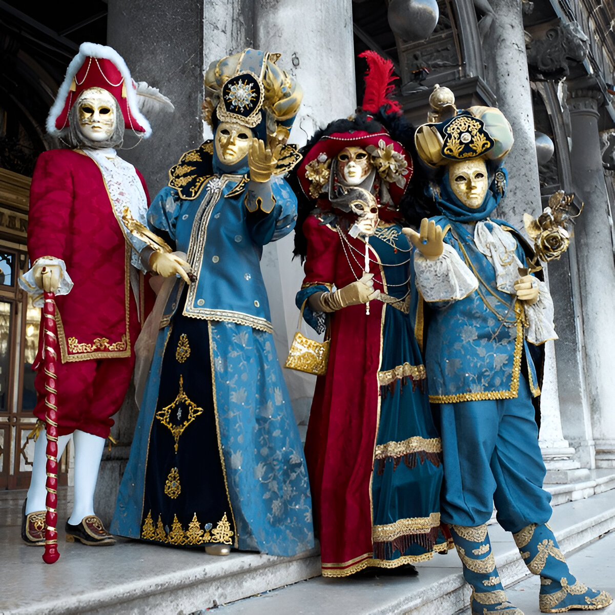 Four masked figures in elaborate Venetian carnival costumes posing beside stone columns