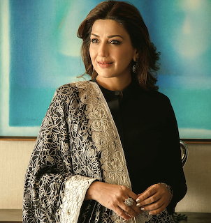 Woman in black outfit with ornate embroidered shawl posing indoors with soft lighting