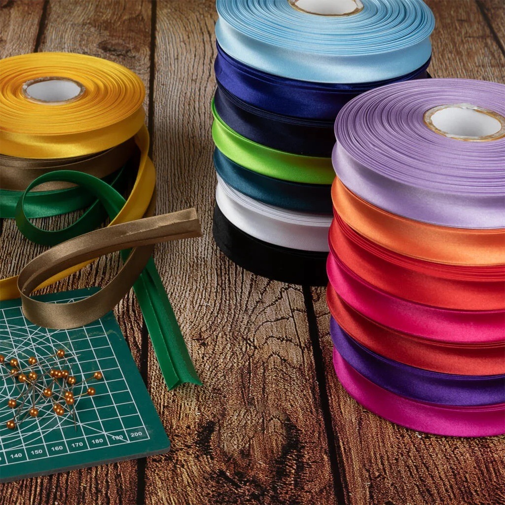 Colorful rolls of satin bias binding with sewing tools on a wooden table