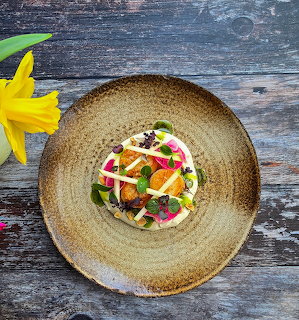 Gourmet dessert with fruits and garnishes on a rustic ceramic plate on a weathered wooden table