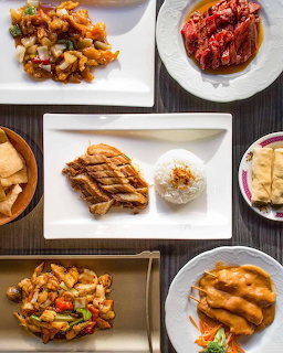 Top-down view of various Asian dishes on white plates arranged on a dark wooden table