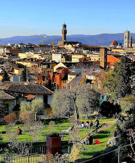 Panoramic view of Florence Italy with Palazzo Vecchio tower, terracotta roofs, and hillside gardens