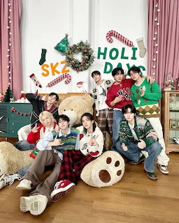 Eight young men in Christmas sweaters posing together with holiday decorations including wreaths and candy canes