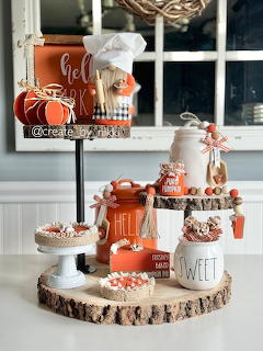 Rustic tiered tray with fall pumpkin decor, candy corn, orange jars, and beaded garland