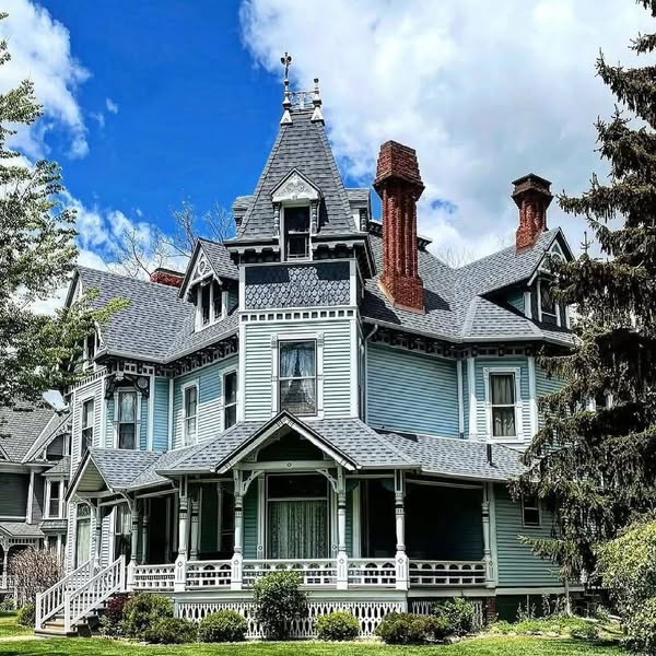 Victorian house with turret, decorative trim, and wraparound porch on a sunny day