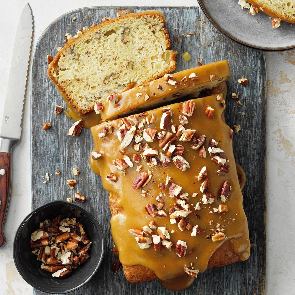 Sliced apple bread with caramel praline topping and pecans on wooden board
