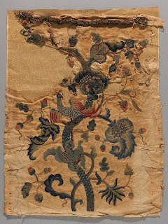 Antique embroidered textile fragment with floral vines and bird motifs on beige fabric