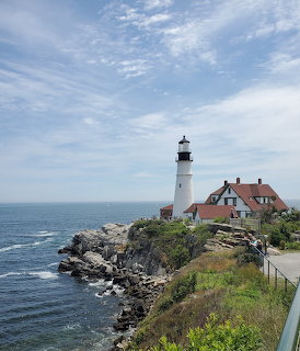 White lighthouse and red-roofed keeper's house on a rocky cliff overlooking the ocean