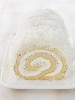 Sliced coconut roulade cake roll with cream filling on white plate