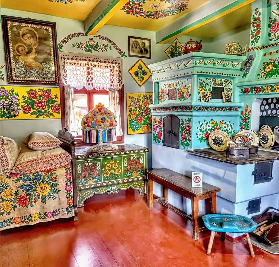 Brightly decorated kitchen with floral painted furniture, turquoise cabinets, and traditional stove in bohemian style