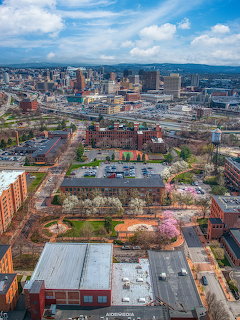 Aerial view of Franklin Square Syracuse NY with bloming trees, brick buildings, and downtown skyline