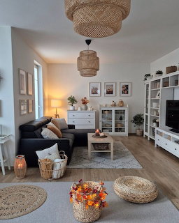 Bright living room with woven pendant lights, white shelving, dark sofa, and fall flowers in basket on wood floor