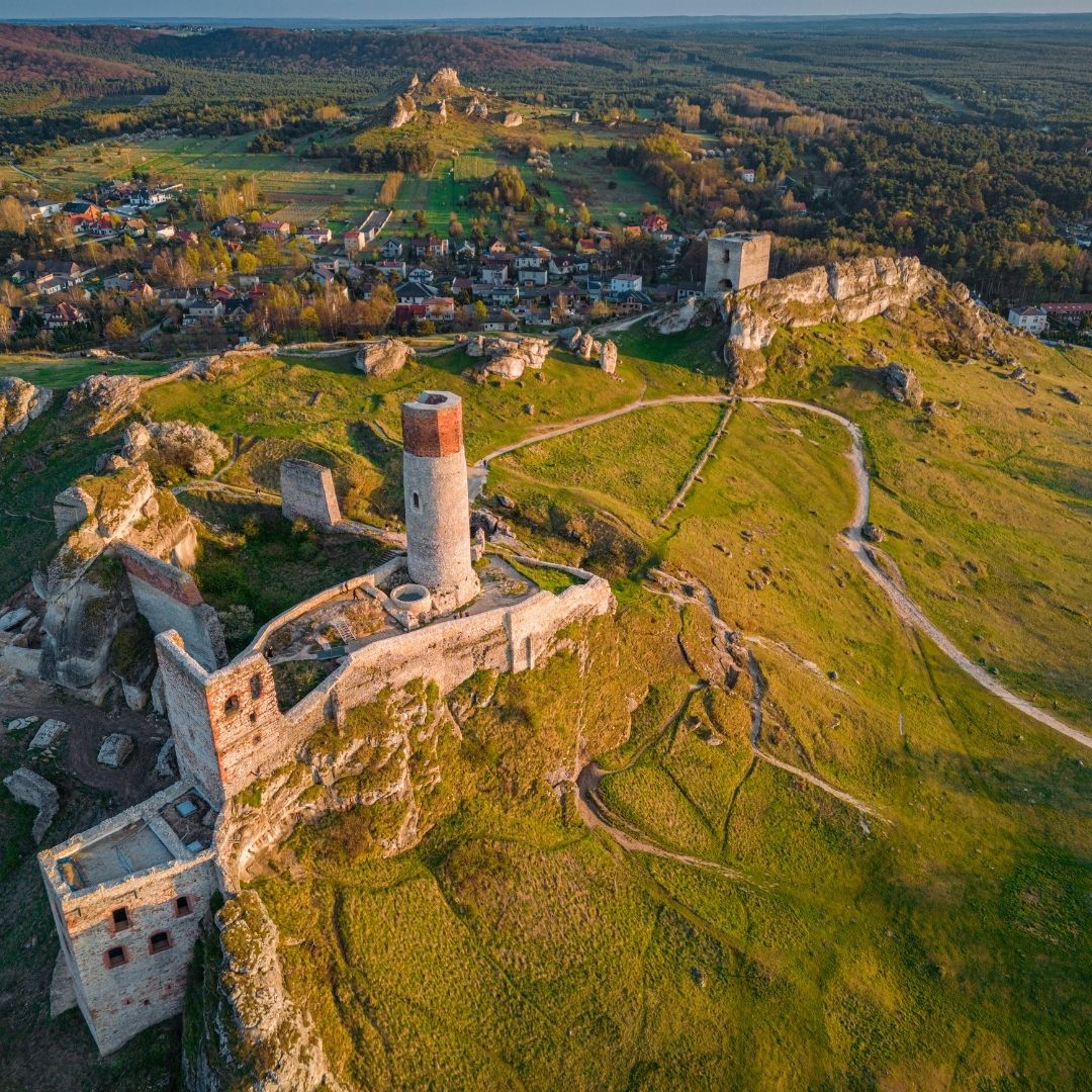 Aerial view of Olsztyn Castle ruins on a rocky hill above a village and forest