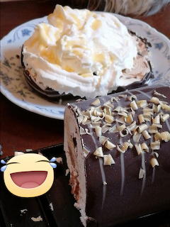 Chocolate cake roll with white chocolate curls beside a plate of whipped cream dessert