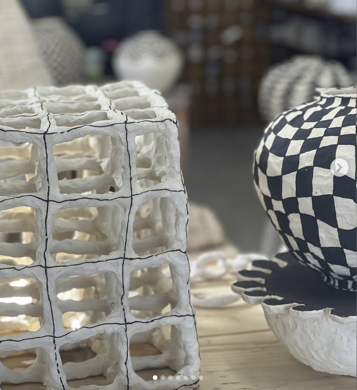 White ceramic lattice cube and checkered vase on a studio table