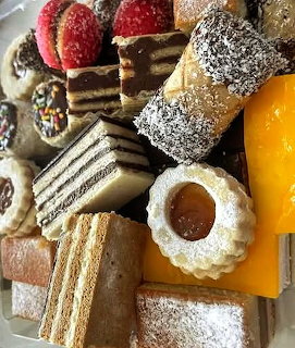 Close-up of assorted pastries, layered cakes, cookies, and powdered sugar desserts