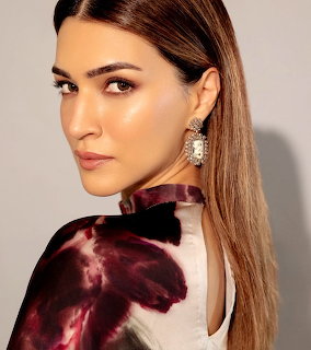 Close-up portrait of a woman with long straight hair, earrings, and a floral satin top