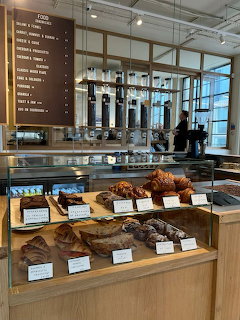 Coffee shop counter with glass pastry display case, menu board, and espresso equipment in background
