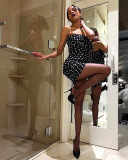Woman in black polka dot dress sitting on stool in contemporary bathroom