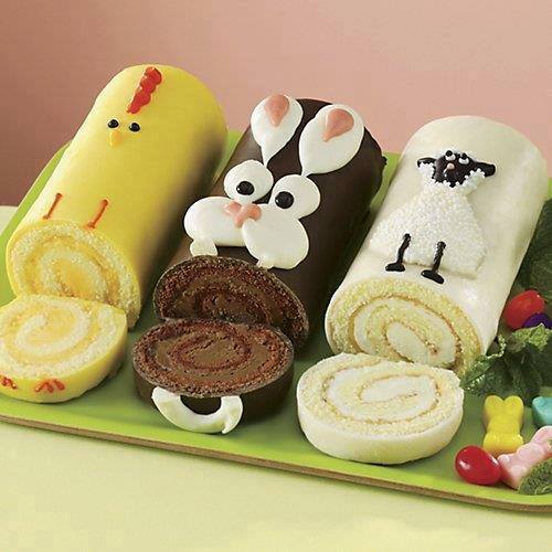 Three character-decorated Swiss roll cakes on a tray with candy