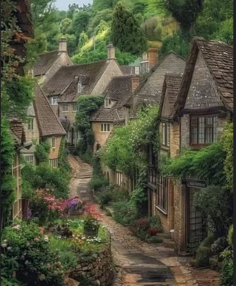 Narrow cobblestone lane lined with old stone cottages and lush gardens in an English village