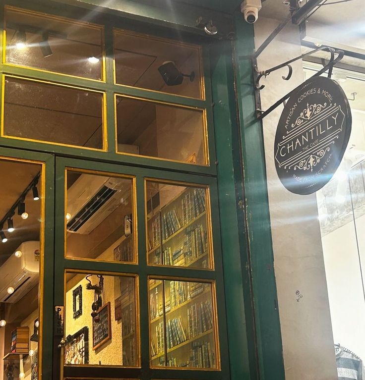 Cafe storefront with green window frames, warm lights, and a hanging sign