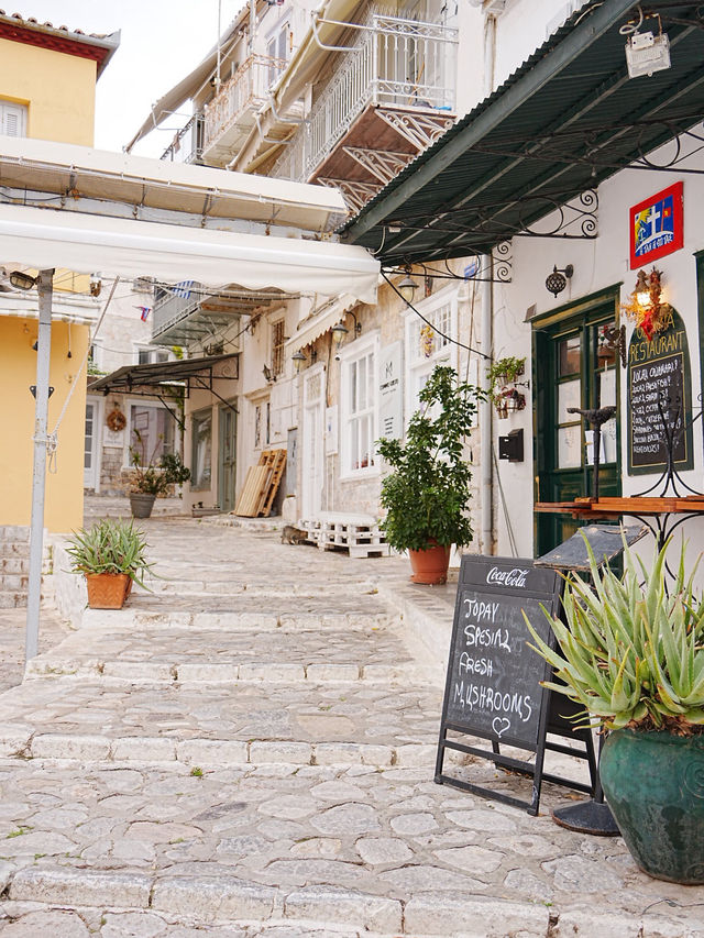 Coblestone pedestrian street with colorful buildings and cafe signs on Hydra Island, Greece