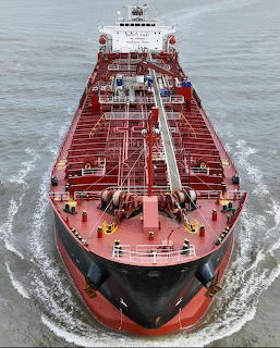Front view of a large red and black oil tanker moving through the sea
