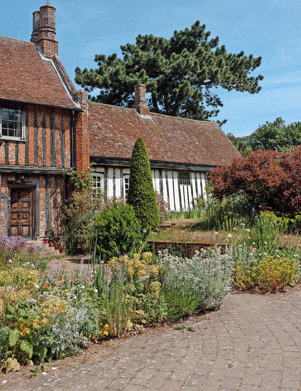 Timber-framed cottage with a flower garden and brick path in Hadleigh, Suffolk