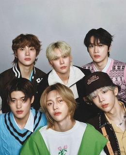 Studio portrait of six young men in colorful outfits against a gray background