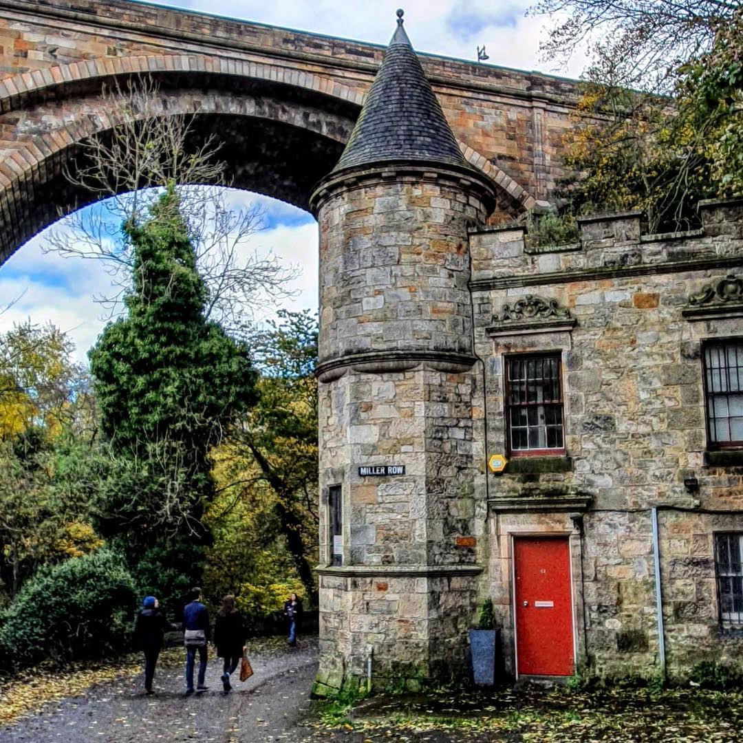 Stone building with turret and red door under railway viaduct arch