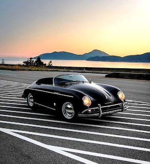 Black vintage Porsche 356A Speedster on a striped road by the water at sunset