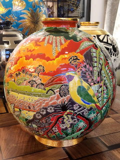 Colorful ceramic vase painted with a toucan bird, tropical flowers, and sunset landscape
