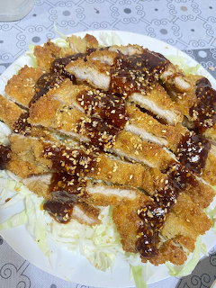 Sliced breaded pork cutlet with sauce and sesame seeds on shredded cabbage