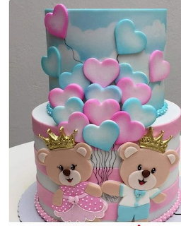 Blue and pink tiered cake with teddy bears, hearts, and gold crowns