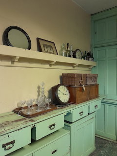 Victorian butler's pantry with mint green cabinetry, white marble counter, antique clock and vintage glassware