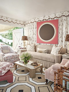 Elegant sitting room with beige sofa, floral armchair, hexagonal coffee table, and pink wall art