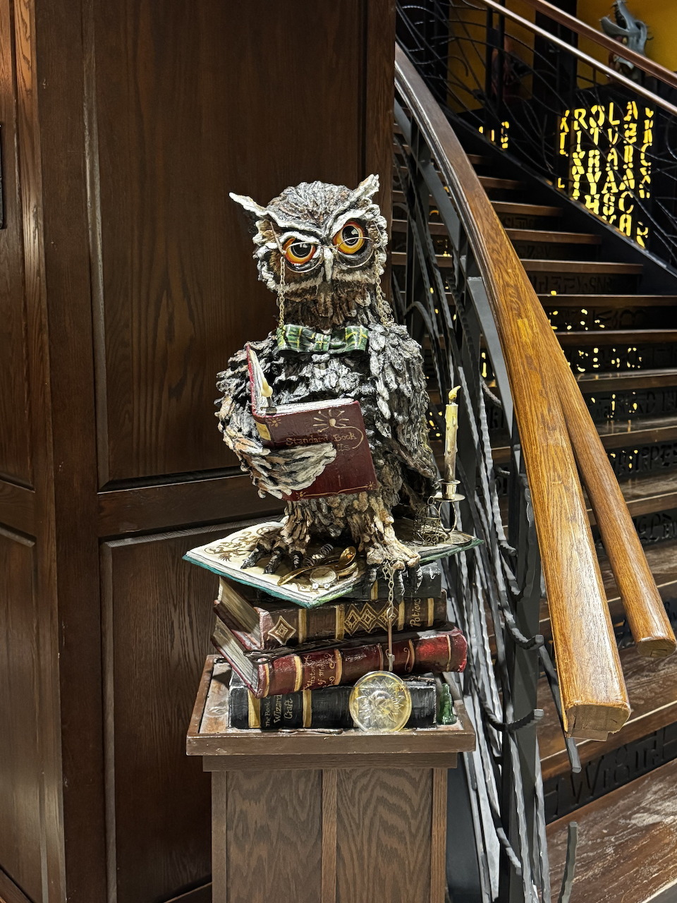 Owl sculpture made of book pages on stacked books beside a wooden staircase