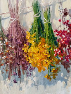 Bunches of colorful dried flowers hanging upside down on a textured white wall