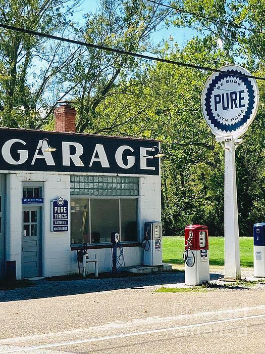 Vintage white garage building with Pure Oil sign and old gas pumps on a sunny day