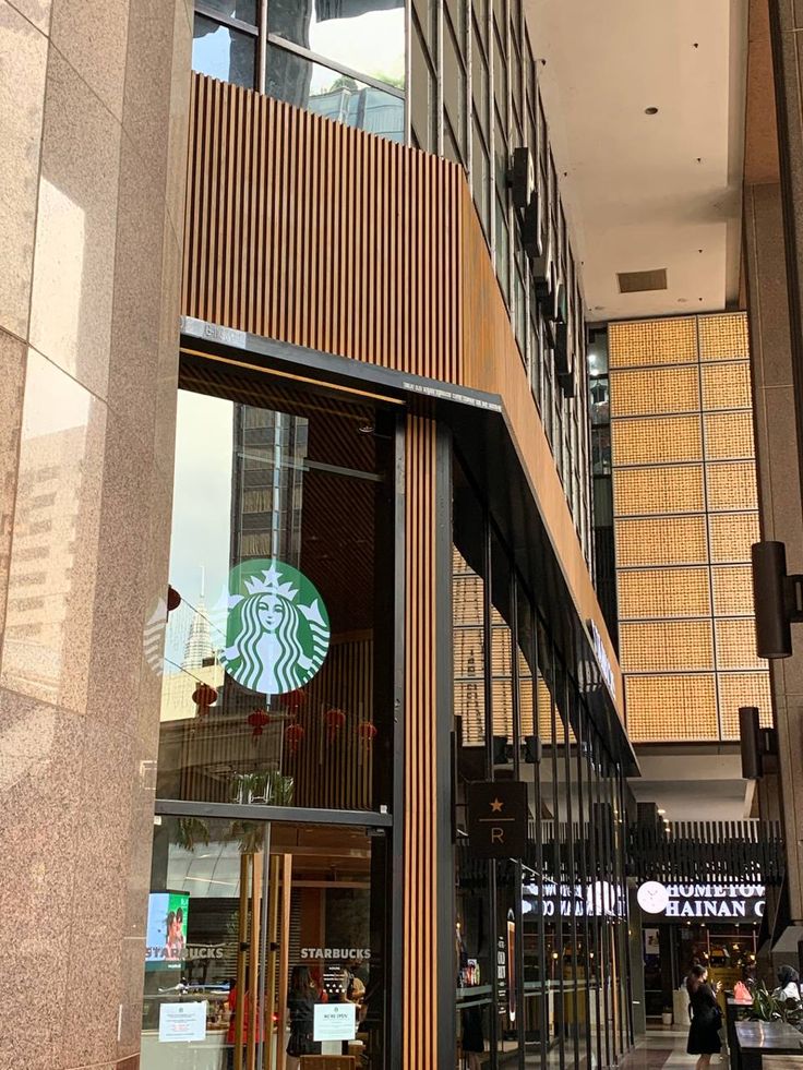 Modern Starbucks storefront with green logo on glass facade and wooden slat panels